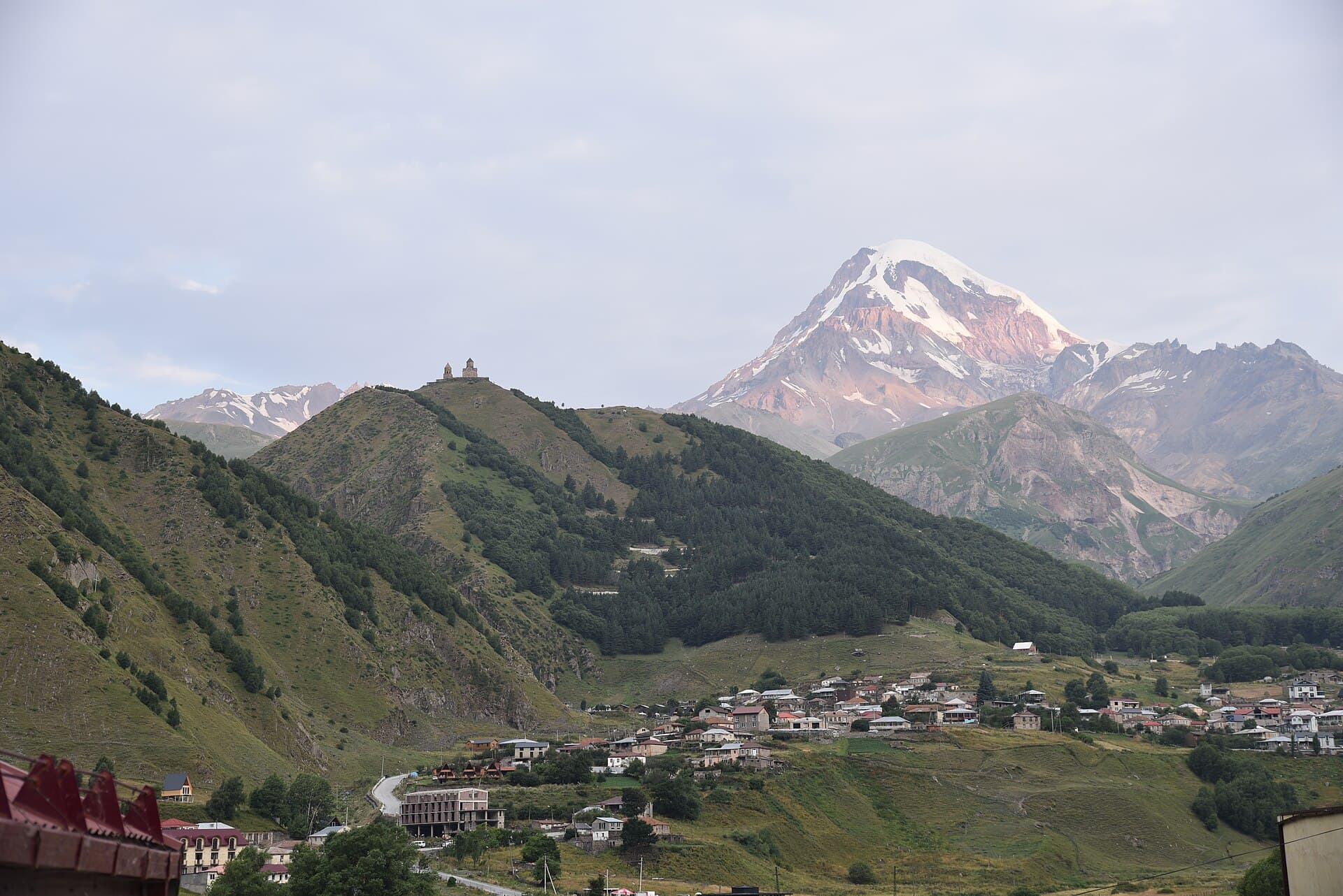 Mount Kazbek rising above Gergeti Trinity Church and a mountain village